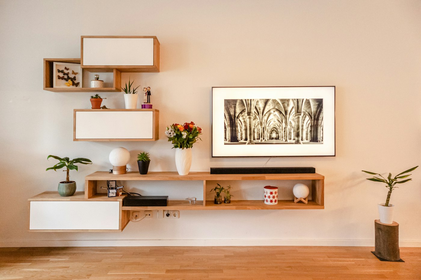 Floating oak shelves and a low media console on a pale wall